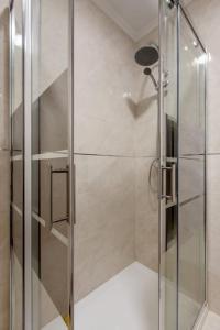 a shower with a glass door in a bathroom at Lovely 3-bedroom condo w/ free parking on premises in Queluz +37 photos