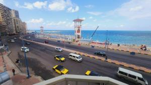eine belebte Stadtstraße mit Autos und einem Uhrturm in der Unterkunft شقة فندقية مكيفة ميامي ع البحر مباشرةً in Alexandria