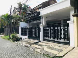 a white house with a black gate on a street at Dehome near Pakuwon Mall in Surabaya