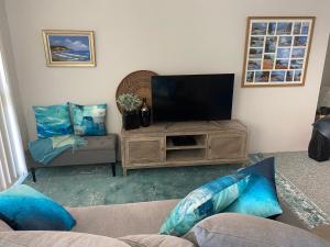 a living room with a television and a couch at Aqua on Bribie 100 metres to Beach and Shops in Bongaree
