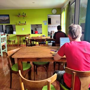 a man sitting at a table using a laptop at Lago Argentino Hostel in El Calafate
