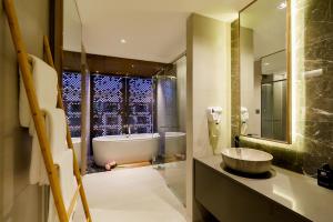 a bathroom with a tub and a sink and a mirror at Fifth Pattaya Jomtien By Shiwalai Int in Jomtien Beach