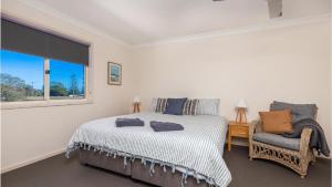 a bedroom with a bed and a chair and a window at Yamba Beach House in Yamba