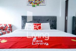 ein rot-weißes Bett mit einem roten Wohnschild darauf in der Unterkunft RedLiving Apartemen Gunung Putri Square - Sansan Room in Parungtandjung + 15 Fotos