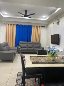 uma sala de estar com sofás e uma televisão de ecrã plano em Klia Redza Homestay Kota Warisan Malay only em Sepang