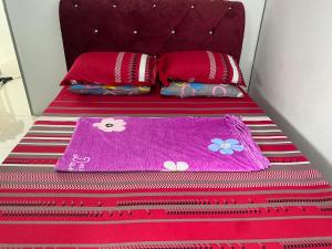 uma cama com cobertores e almofadas vermelhos e rosa em Klia Redza Homestay Kota Warisan Malay only em Sepang