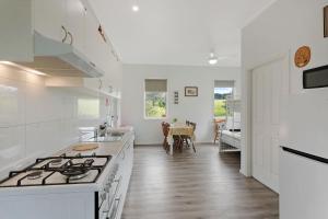 a white kitchen with a stove and a table at Henkley Cottage 1 Isaiah in Central Tilba