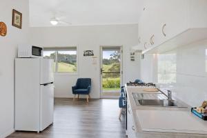 eine weiße Küche mit einer Spüle und einem Kühlschrank in der Unterkunft Henkley Cottage 1 Isaiah in Central Tilba