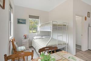 ein Schlafzimmer mit einem Etagenbett und einem Tisch in der Unterkunft Henkley Cottage 1 Isaiah in Central Tilba