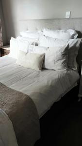 ein großes Bett mit weißer Bettwäsche und Kissen darauf in der Unterkunft Dragonflycottagebnb in Grovetown