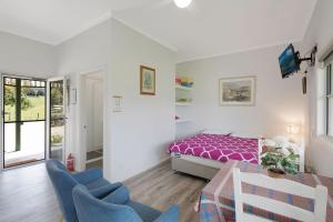 a bedroom with a bed and two blue chairs at Henkley Cottage 2 Jeremiah in Central Tilba