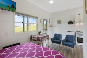 a bedroom with a purple bed and two blue chairs at Henkley Cottage 2 Jeremiah in Central Tilba