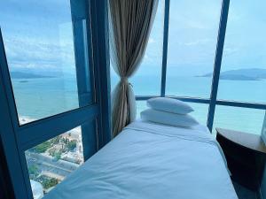 a bed in a room with a view of the ocean at PANORAMA Nha Trang by HLG in Nha Trang