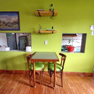 a table and chairs in a room with a green wall at Lago Argentino B&B in El Calafate