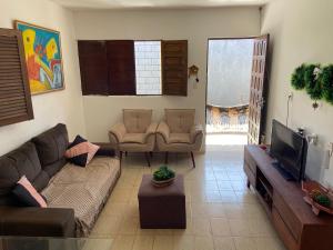 ein Wohnzimmer mit einem Sofa und einem TV in der Unterkunft Casa de Praia na Barra de São Miguel - AL in Barra de São Miguel