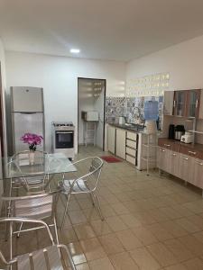 eine Küche mit einem Glastisch und Stühlen im Zimmer in der Unterkunft Casa de Praia na Barra de São Miguel - AL in Barra de São Miguel