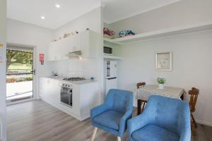 a kitchen with two blue chairs and a table at Henkley Cottage 3 Ezekiel in Central Tilba