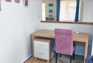 einen Schreibtisch mit einem Stuhl neben einem Holztisch in der Unterkunft Harrys Haven Harrington in Harrington