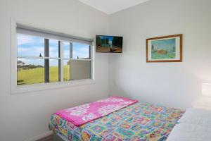 a bedroom with a bed and a window at Henkley Cottage 3 Ezekiel in Central Tilba
