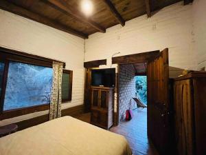 Schlafzimmer mit einem Bett, einem TV und einem Fenster in der Unterkunft Cabaña en Malinalco El rincón de Anita in Malinalco