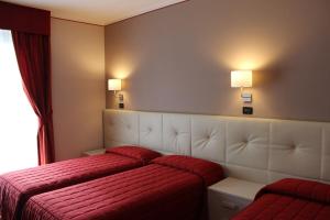 a hotel room with a bed and two lamps on the wall at Hotel Adler in Menaggio
