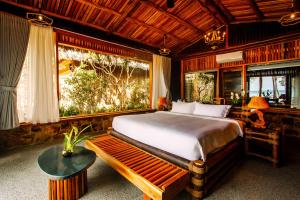 a bedroom with a bed and a bench and a window at Ocean Bay Phu Quoc Resort and Spa in Phu Quoc