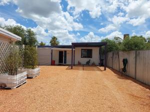 a house with a fence and a dirt yard at Lavender Cottage - At home in Lightning Ridge in Lightning Ridge