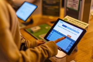 a person pointing at a tablet computer on a table at UNPLAN Kagurazaka in Tokyo