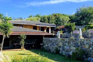 una casa con una pared de piedra y una valla en Villa Capodorso, Palau Porto Pollo, en Palau
