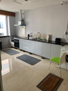 a kitchen with white cabinets and a green chair at Garden Hostel in Auckland