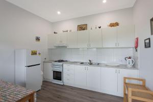a kitchen with white cabinets and a white refrigerator at Henkley Cottage 3 Ezekiel in Central Tilba