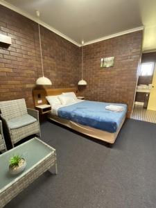 a bedroom with a bed and a chair in a room at Golden West Motor Inn in Miles