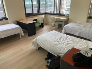 um quarto com 2 camas, uma secretária e uma mesa em Garden Hostel em Auckland