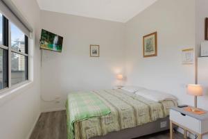 a white bedroom with a bed and a window at Henkley Cottage 4 Daniel in Central Tilba