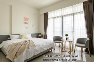 een slaapkamer met een bed en 2 stoelen en een tafel bij Mini House B&B in Luodong