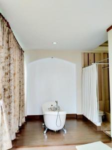 uma banheira branca na casa de banho com cortinas em Villa Gathering Yuni Syahla em Citaringgul 1