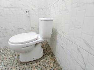 - białą toaletę w łazience wyłożonej białymi kafelkami w obiekcie Labinda Homestay Caruban Mitra RedDoorz w mieście Madiun