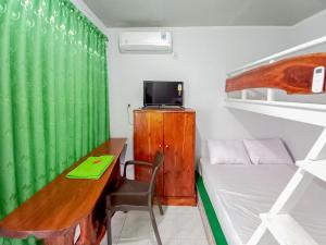 Mały pokój z biurkiem i zieloną zasłoną w obiekcie Labinda Homestay Caruban Mitra RedDoorz w mieście Madiun