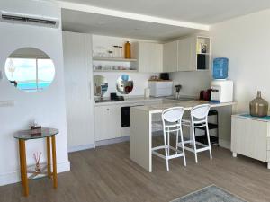 a kitchen with white cabinets and a table and stools at Studio Deluxe in Bora Bora