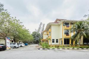 a building with cars parked in a parking lot at Terengganu Equestrian Resort in Kuala Terengganu