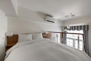 Un dormitorio con una gran cama blanca y una ventana en Anping Kensington Hotel en Anping