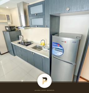 a small kitchen with a refrigerator and a sink at SPACIOUS 2BR NEAR MOA, SOLAIRE CASINO AND PASAY AREA in Manila