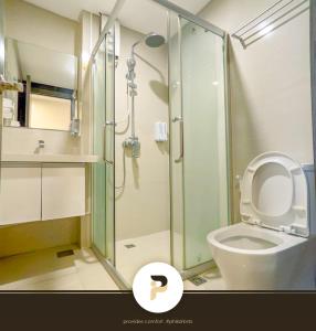 a bathroom with a toilet and a glass shower at SPACIOUS 2BR NEAR MOA, SOLAIRE CASINO AND PASAY AREA in Manila