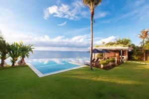 a house with a swimming pool and a palm tree at The Ungasan Clifftop Resort in Uluwatu