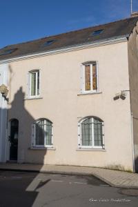 a white building with three windows on a street at Appartement Luna Hypercentre Gare à 300m in Pontchâteau