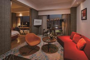 Habitación de hotel con sofá rojo y sala de estar. en Paradox Kunshan, en Kunshan