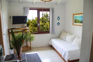 sala de estar con sofá y ventana en Condomínio Aldeia dos Anjosdo Rosa, en Praia do Rosa