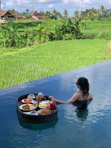 uma mulher na água com um tabuleiro de comida em Umah Tirta em Ubud