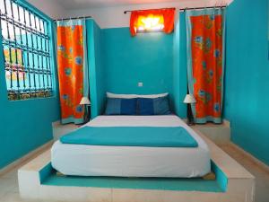 een slaapkamer met een bed met blauwe muren en oranje gordijnen bij La Kasbah du Paradis in Aksri