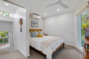 a white bedroom with a bed and a window at Little cove gem - walking distance to the most famous Noosa beach! in Noosa Heads